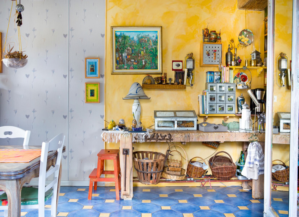 Cette image montre une salle à manger ouverte sur le salon bohème de taille moyenne avec un mur jaune, tomettes au sol et un sol bleu.
