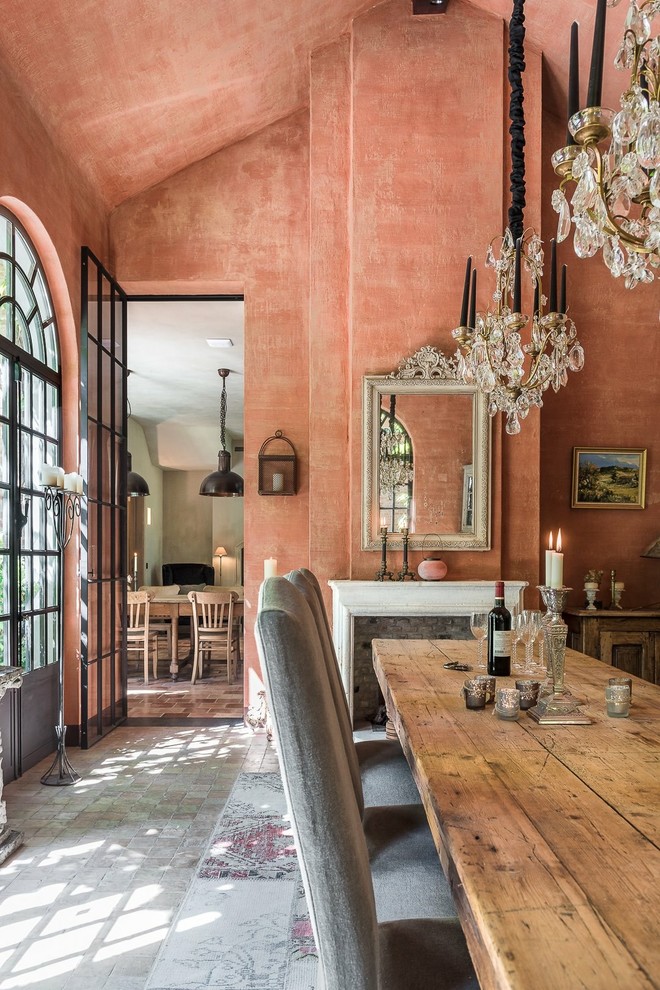 Cette photo montre une salle à manger méditerranéenne fermée avec une cheminée standard, un sol gris, un mur orange et un manteau de cheminée en pierre.