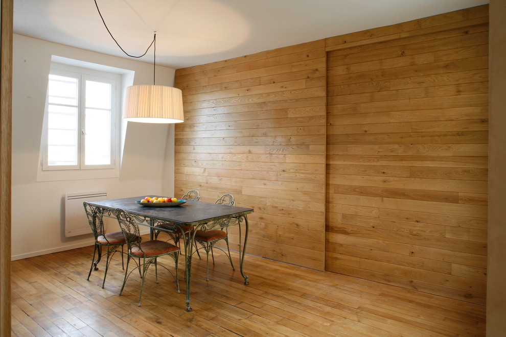 Cette image montre une salle à manger design fermée et de taille moyenne avec un mur blanc, un sol en bois brun et aucune cheminée.