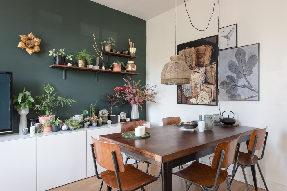 Aménagement d'une salle à manger éclectique avec un mur vert et parquet clair.