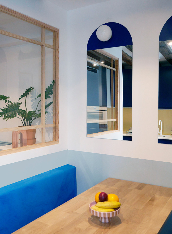 Idee per un piccolo angolo colazione minimalista con pareti blu, parquet chiaro, pavimento beige e travi a vista