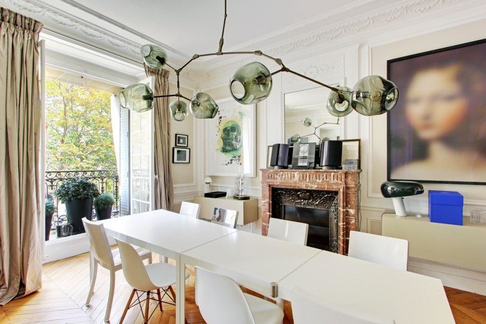 Inspiration pour une salle à manger design avec un mur blanc, un sol en bois brun et une cheminée standard.
