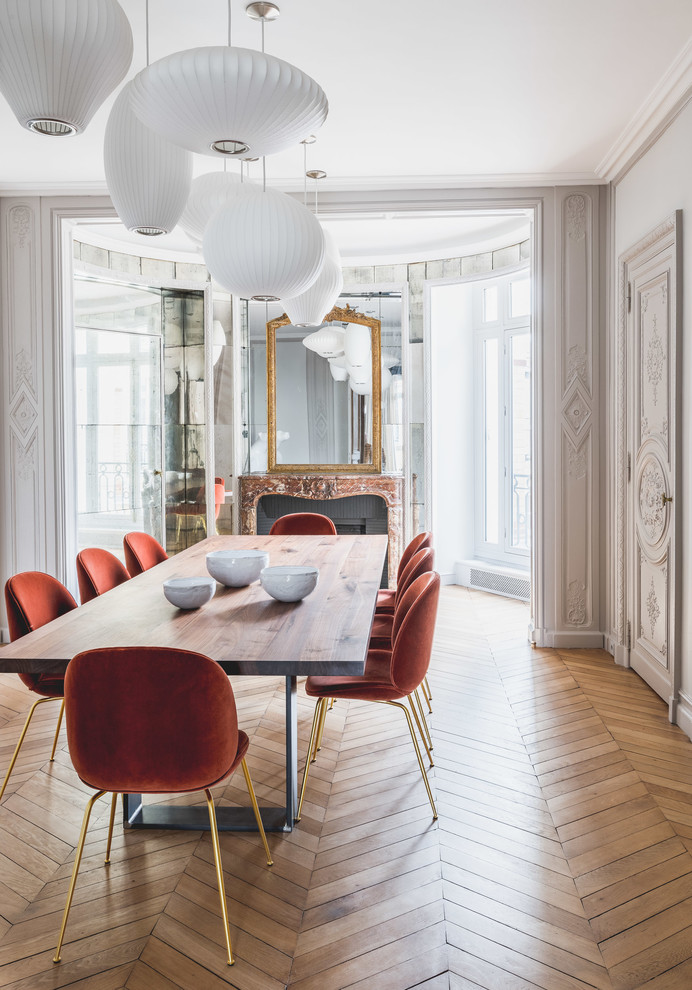 Modernes Esszimmer mit weißer Wandfarbe, braunem Holzboden, Kamin, Kaminumrandung aus Backstein und braunem Boden in Paris
