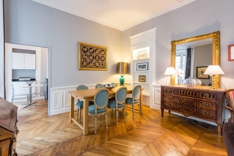 Inspiration pour une salle à manger ouverte sur le salon traditionnelle de taille moyenne avec un mur gris et un sol en bois brun.