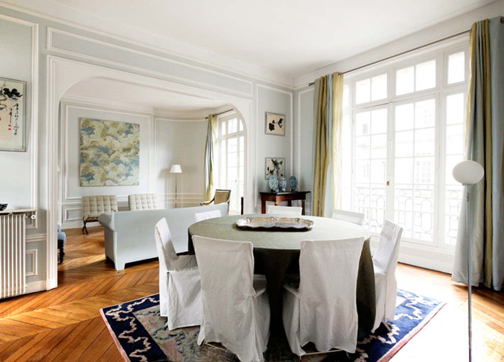 Réalisation d'une grande salle à manger tradition avec un mur blanc, parquet clair et un sol marron.