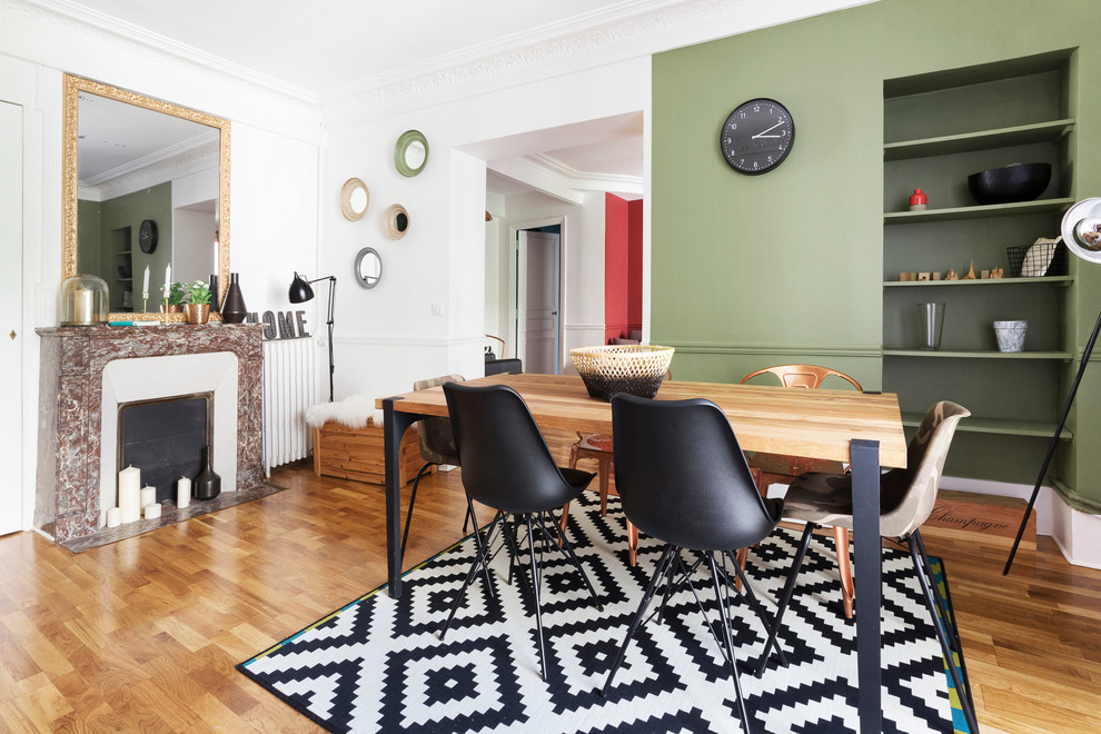 Inspiration pour une salle à manger design fermée et de taille moyenne avec un mur vert, parquet clair, une cheminée standard et éclairage.