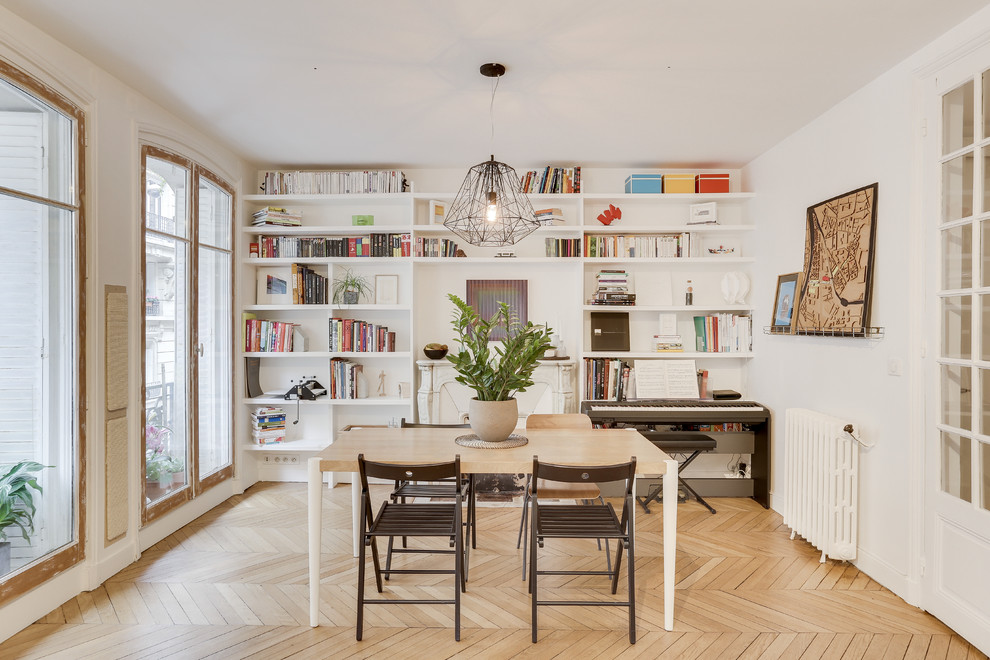 Inspiration pour une salle à manger nordique de taille moyenne et fermée avec un mur blanc, parquet clair, une cheminée standard, un manteau de cheminée en pierre et un sol beige.