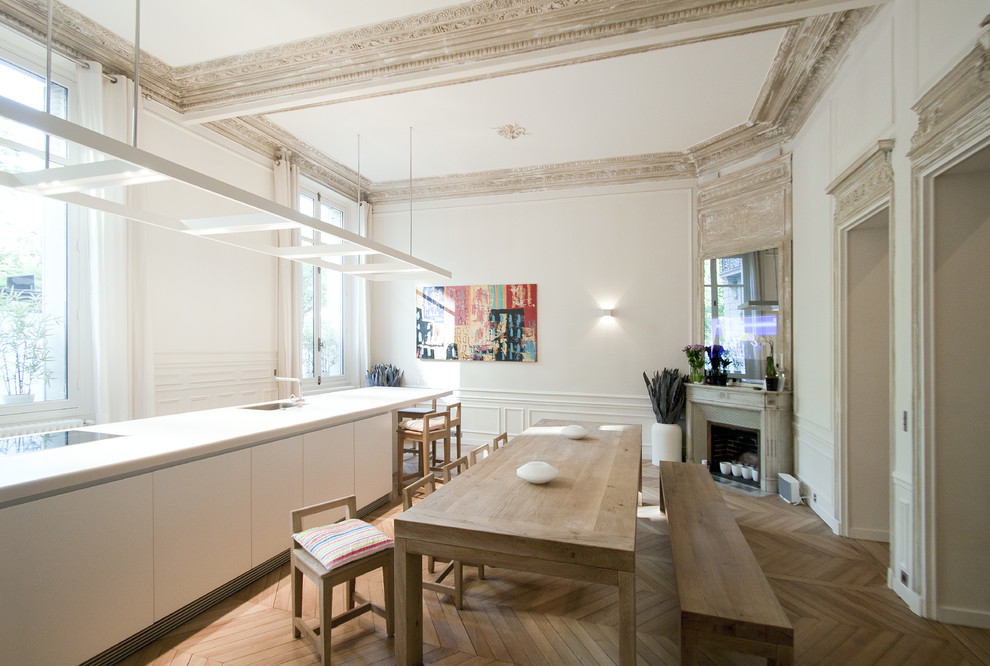 На фото: большая кухня-столовая в современном стиле с белыми стенами и паркетным полом среднего тона