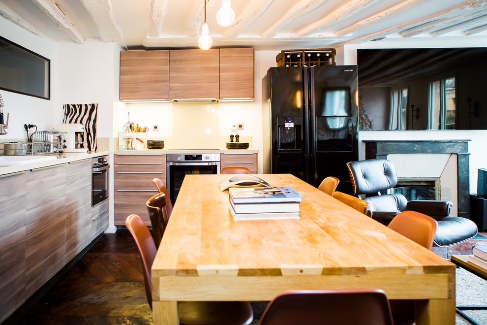 Cette image montre une grande salle à manger ouverte sur la cuisine avec un mur blanc, parquet foncé et une cheminée standard.