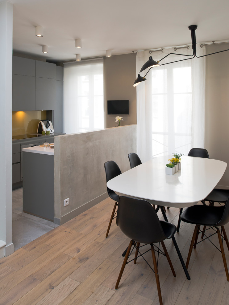Cette image montre une salle à manger ouverte sur la cuisine design avec un mur gris et un sol marron.