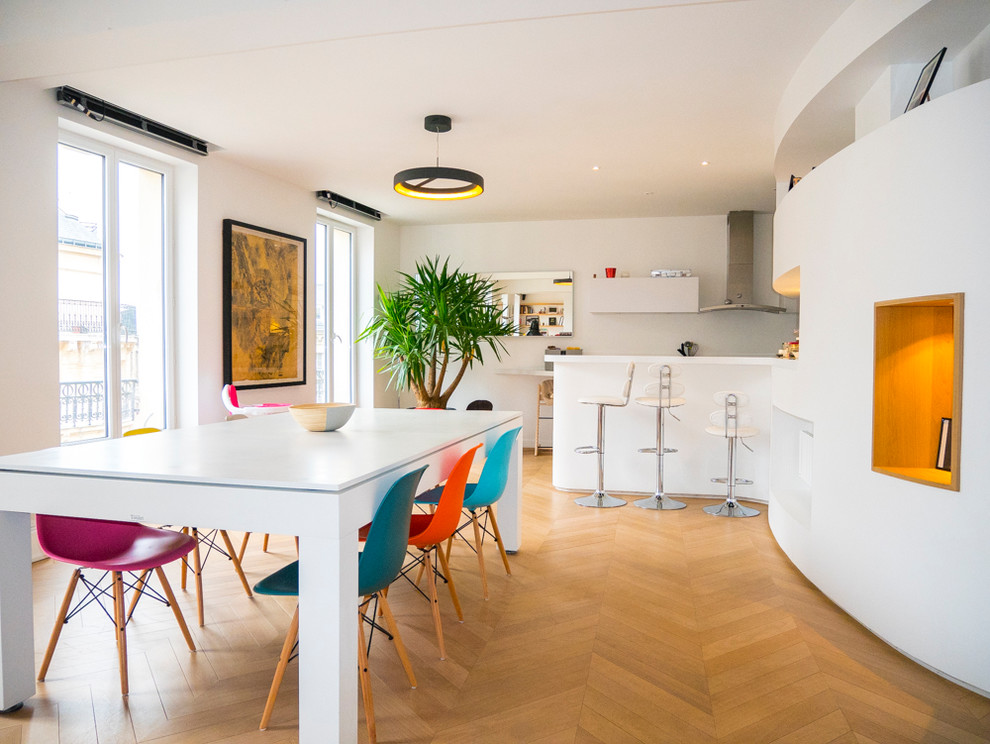 Inspiration pour une salle à manger ouverte sur la cuisine design avec un mur blanc, un sol en bois brun et aucune cheminée.