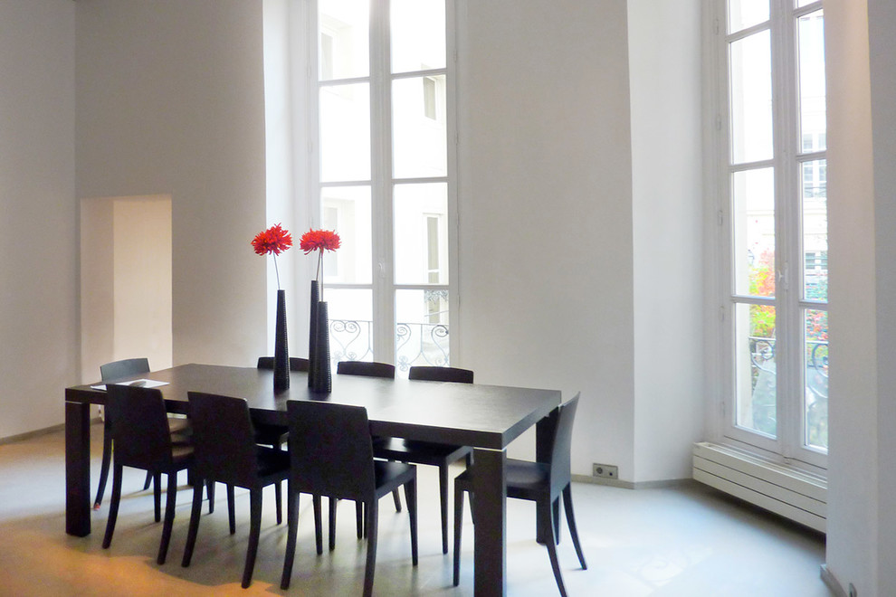 Inspiration pour une grande salle à manger design avec un mur blanc et sol en béton ciré.