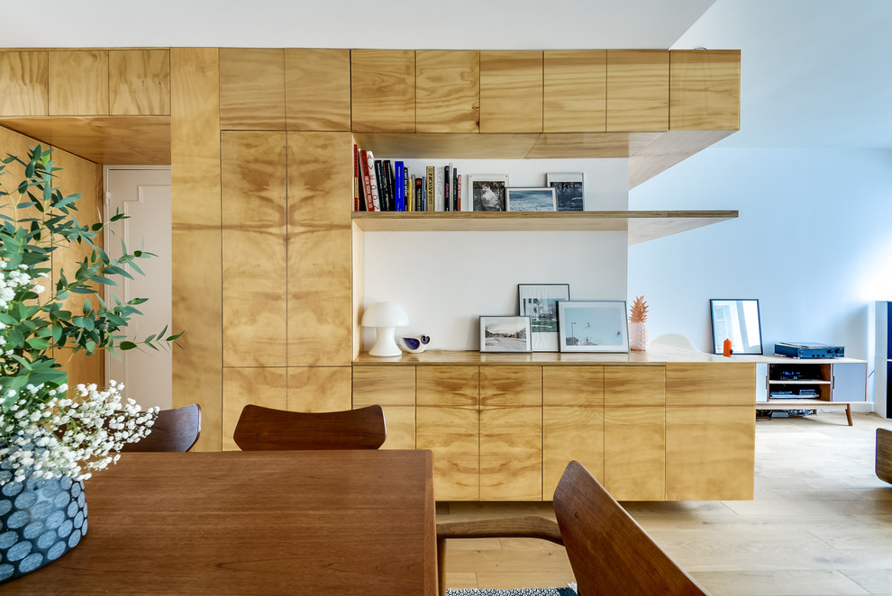 Large contemporary open plan dining room in Paris with white walls, light hardwood flooring, no fireplace and feature lighting.