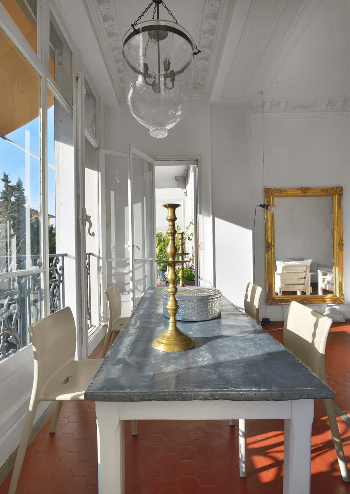 На фото: столовая среднего размера в средиземноморском стиле с белыми стенами и полом из терракотовой плитки