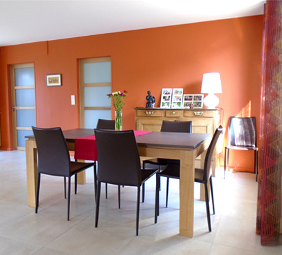 Mittelgroßes Modernes Esszimmer mit oranger Wandfarbe, dunklem Holzboden und Tunnelkamin in Angers