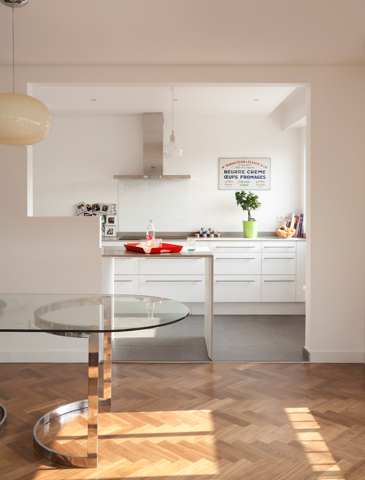 Immagine di una sala da pranzo aperta verso la cucina minimal con pareti bianche e pavimento in legno massello medio