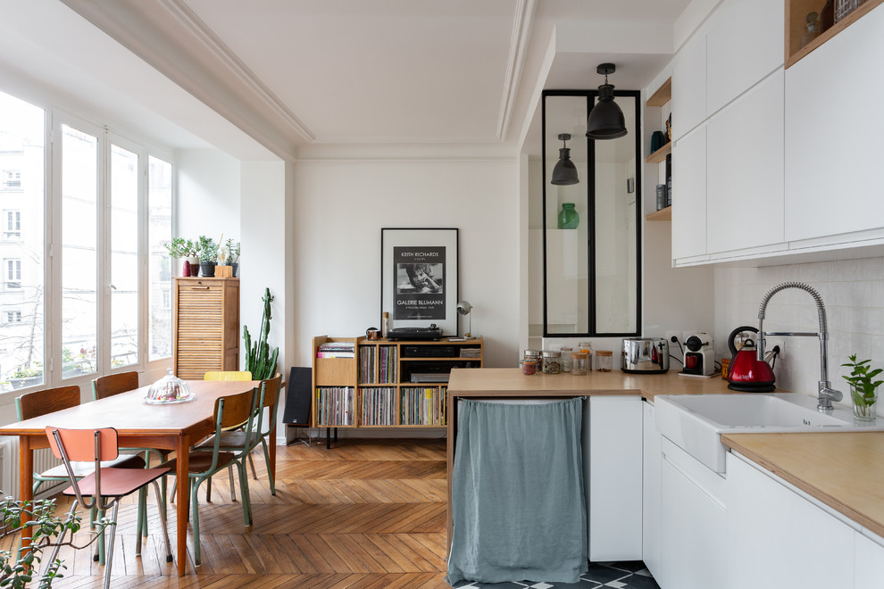 パリにあるお手頃価格の中くらいな北欧スタイルのおしゃれなダイニングキッチン (白い壁、無垢フローリング、暖炉なし、茶色い床) の写真