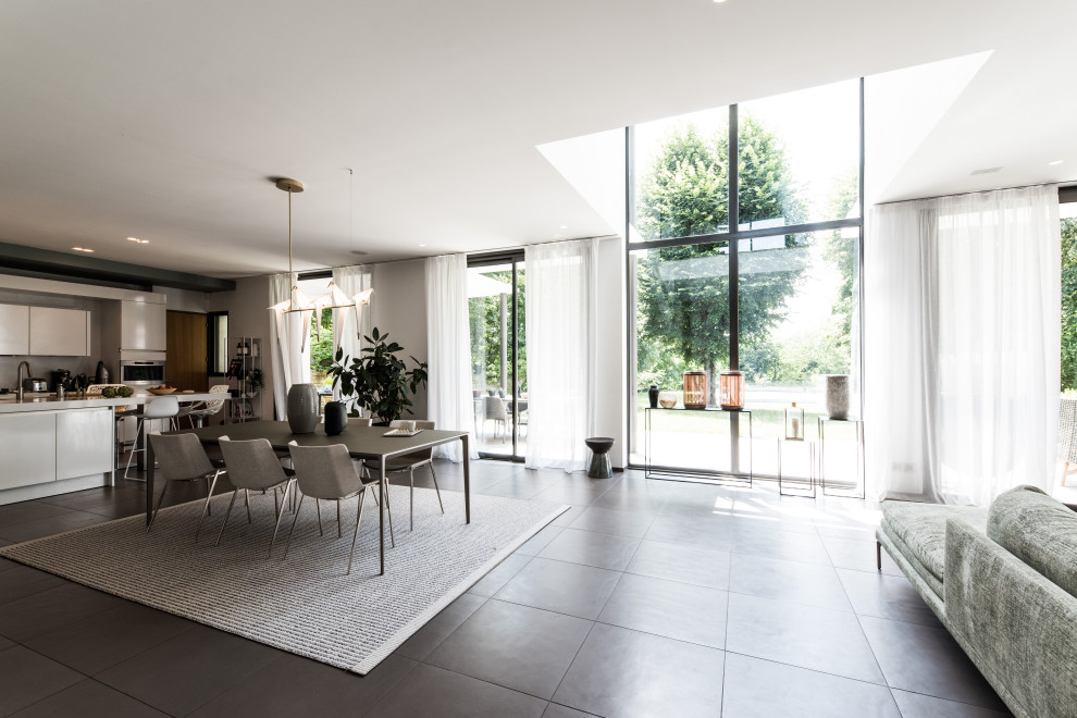 Immagine di una sala da pranzo aperta verso il soggiorno contemporanea con pareti grigie e pavimento grigio