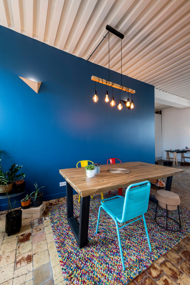 Cette image montre une salle à manger design avec un mur bleu et tomettes au sol.