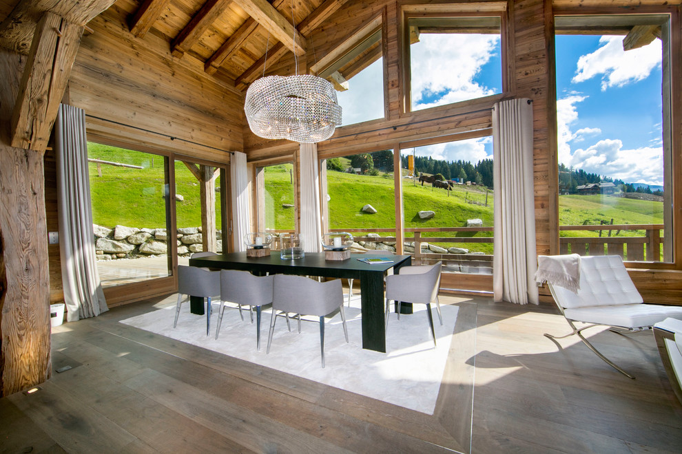Immagine di una grande sala da pranzo aperta verso il soggiorno eclettica con pareti marroni e pavimento in legno massello medio