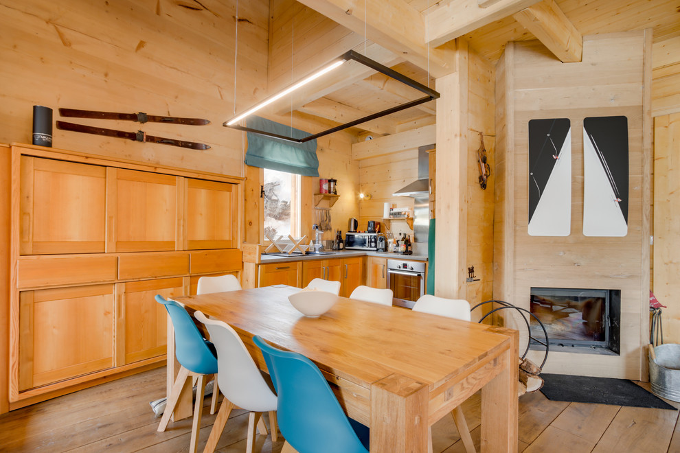 Exemple d'une petite salle à manger ouverte sur le salon tendance avec parquet clair, une cheminée d'angle et un manteau de cheminée en bois.