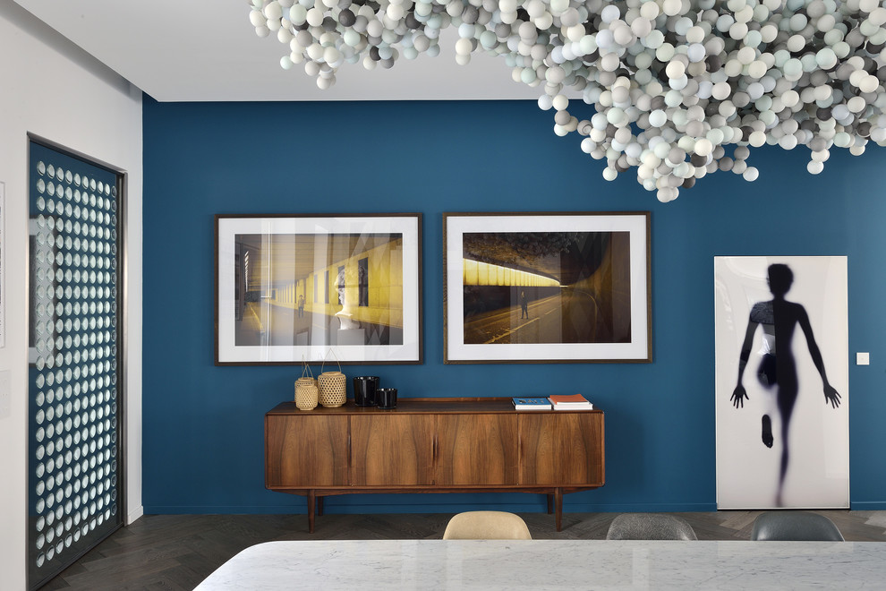 Cette image montre une salle à manger design de taille moyenne avec un mur bleu et parquet foncé.
