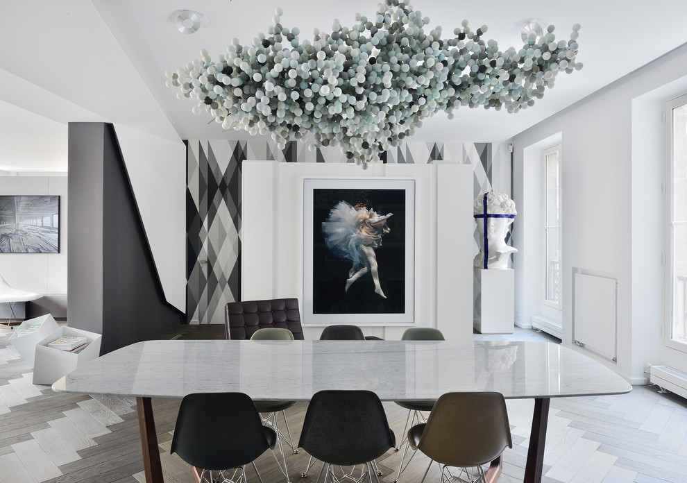 This is an example of a large contemporary open plan dining room in Paris with white walls, light hardwood flooring and no fireplace.