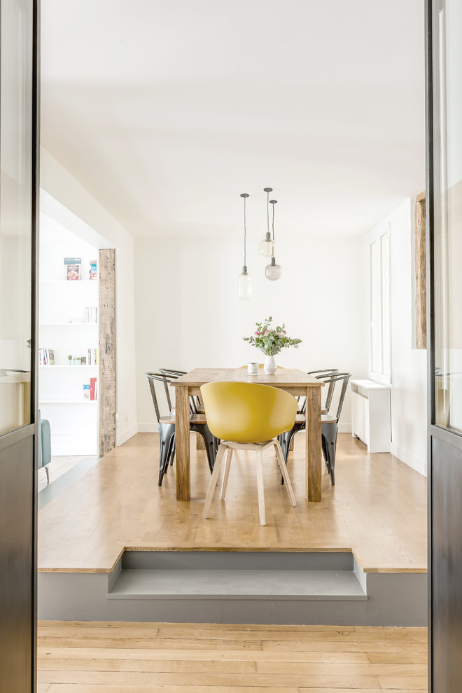 Aménagement d'une salle à manger ouverte sur le salon contemporaine de taille moyenne avec un mur blanc, un sol en bois brun, aucune cheminée et un sol marron.