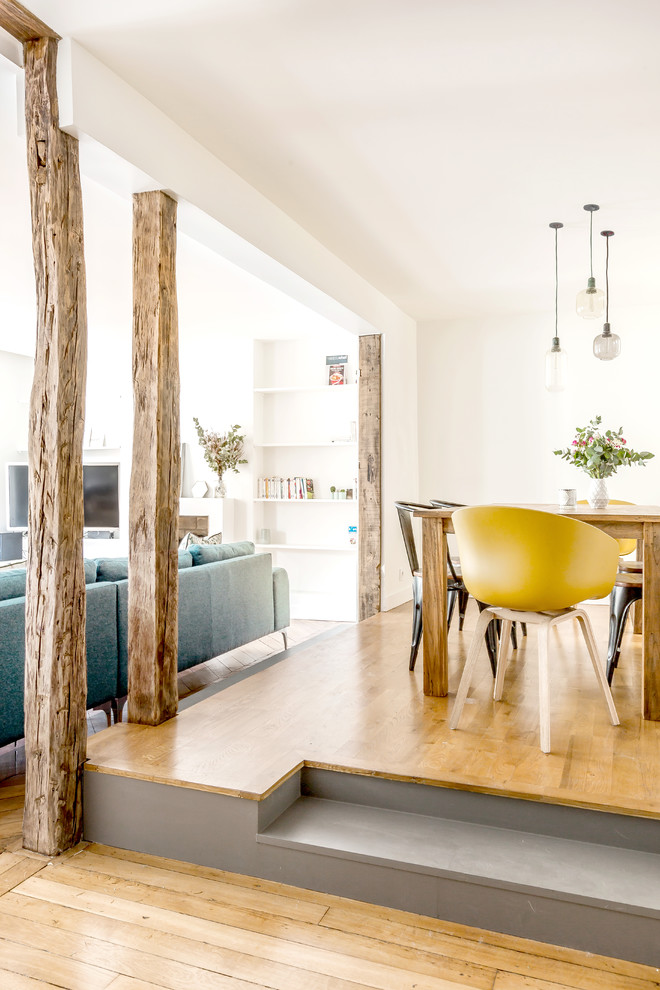 Inspiration pour une salle à manger ouverte sur le salon design de taille moyenne avec un mur blanc, un sol en bois brun et un sol marron.