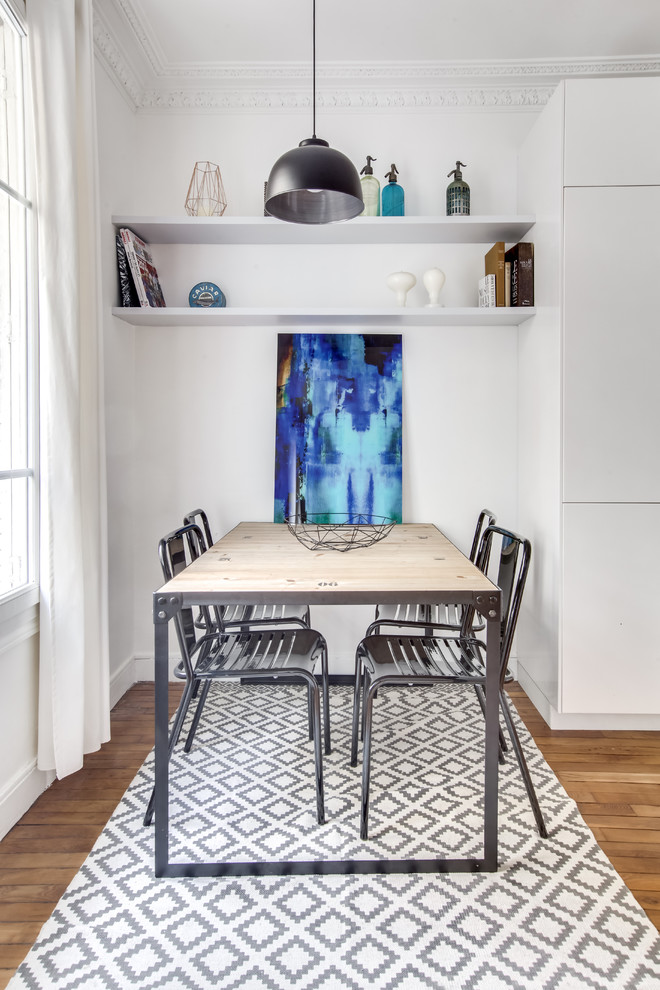 Cette image montre une salle à manger ouverte sur la cuisine traditionnelle avec un mur blanc et un sol en bois brun.