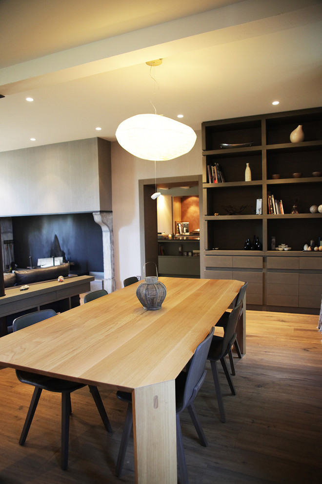 Cette photo montre une grande salle à manger ouverte sur le salon tendance avec un sol en bois brun et un mur blanc.