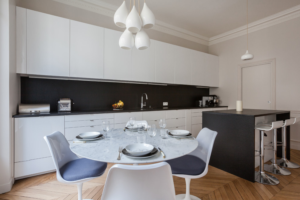 Exemple d'une salle à manger ouverte sur la cuisine tendance de taille moyenne avec un mur blanc et un sol en bois brun.