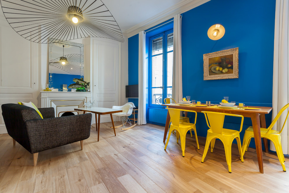 Cette image montre une salle à manger ouverte sur le salon design avec un mur bleu et parquet clair.