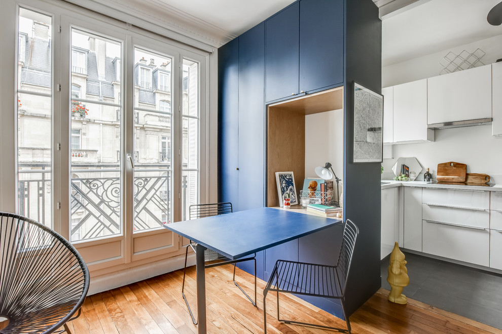 Modelo de comedor contemporáneo abierto con paredes azules y suelo de madera en tonos medios