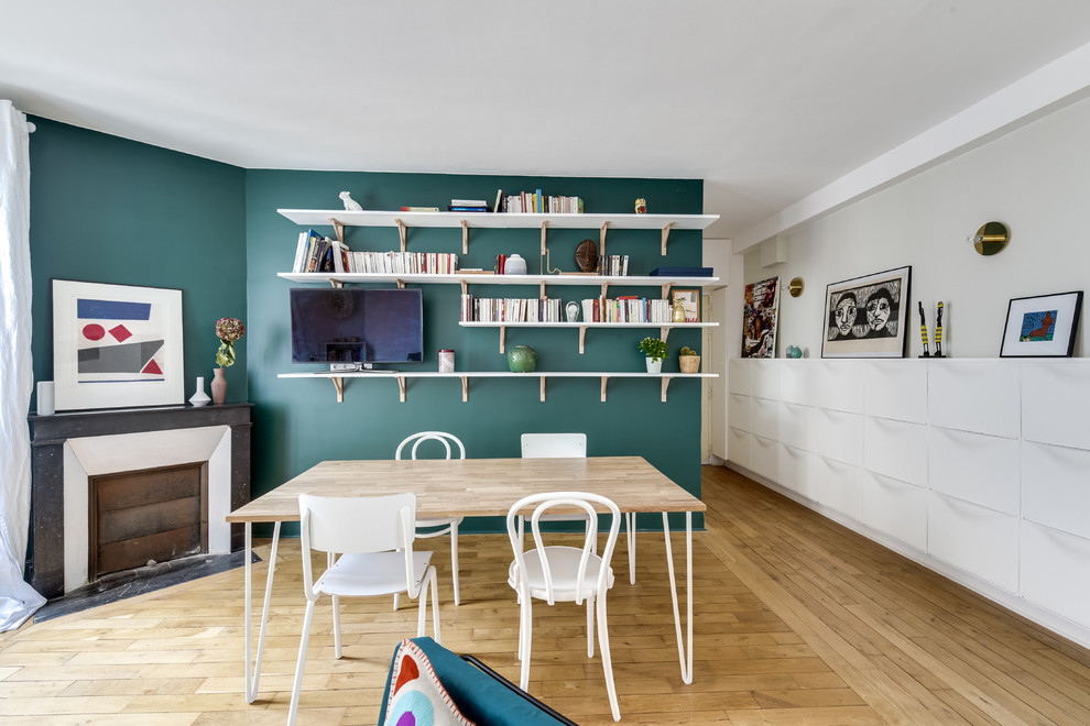 Aménagement d'une salle à manger ouverte sur le salon contemporaine avec un mur vert, parquet clair, une cheminée d'angle et un sol beige.