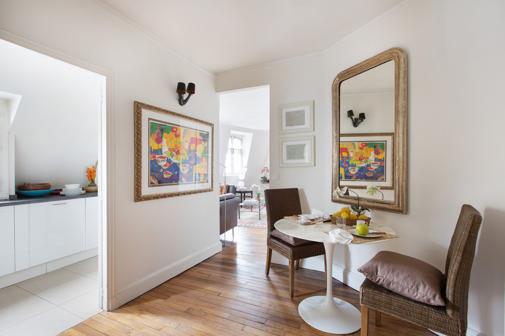 Small eclectic open plan dining room in Paris with white walls and medium hardwood flooring.