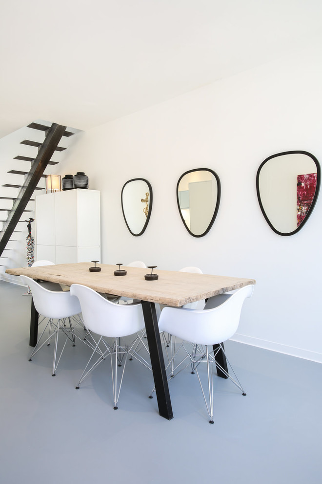 Cette photo montre une salle à manger tendance de taille moyenne avec un mur blanc, sol en béton ciré, aucune cheminée et un sol gris.