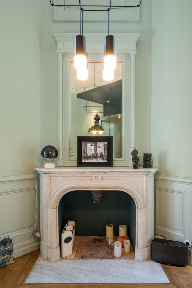 リヨンにあるお手頃価格の中くらいなトラディショナルスタイルのおしゃれなLDK (緑の壁、淡色無垢フローリング、コーナー設置型暖炉、木材の暖炉まわり、ベージュの床) の写真