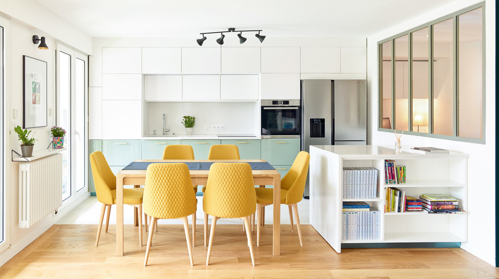 Foto di una grande sala da pranzo aperta verso la cucina minimal con pareti bianche, pavimento marrone e pavimento in legno massello medio