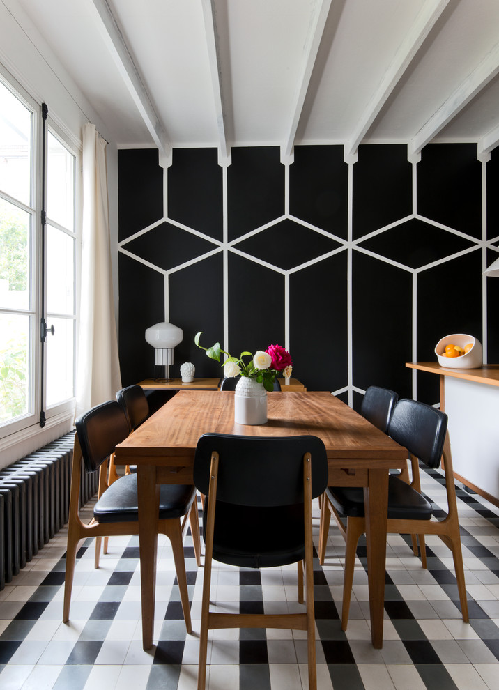 Contemporary dining room in Paris with black walls and feature lighting.