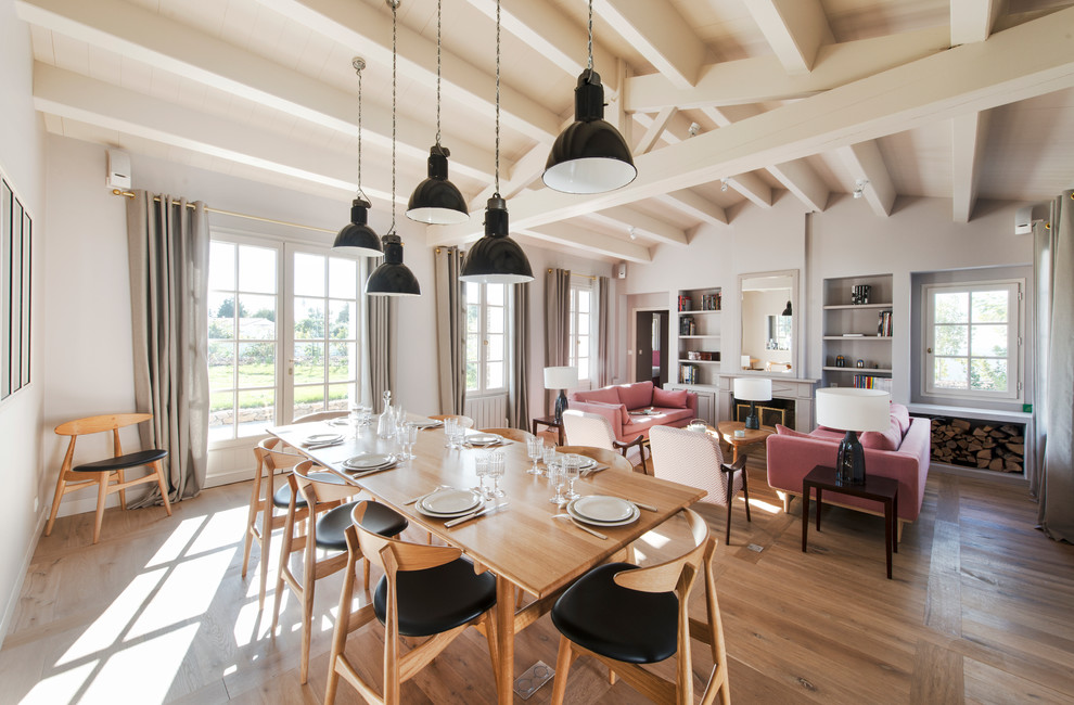 Immagine di una grande sala da pranzo aperta verso il soggiorno scandinava con pareti bianche e pavimento in legno massello medio