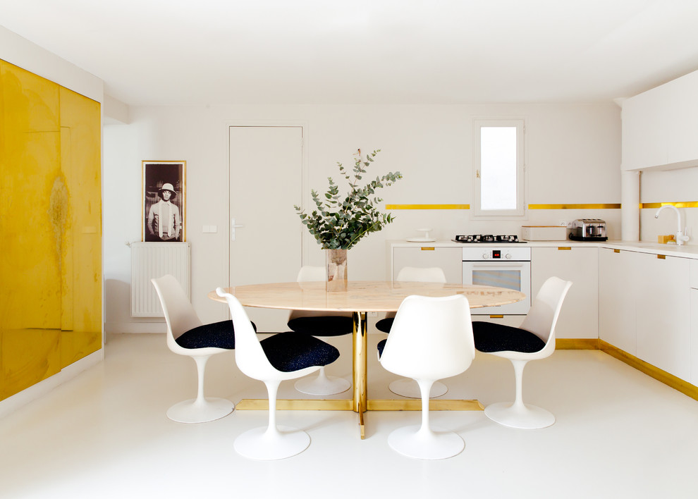 Cette image montre une grande salle à manger ouverte sur la cuisine design avec un mur blanc et un sol blanc.