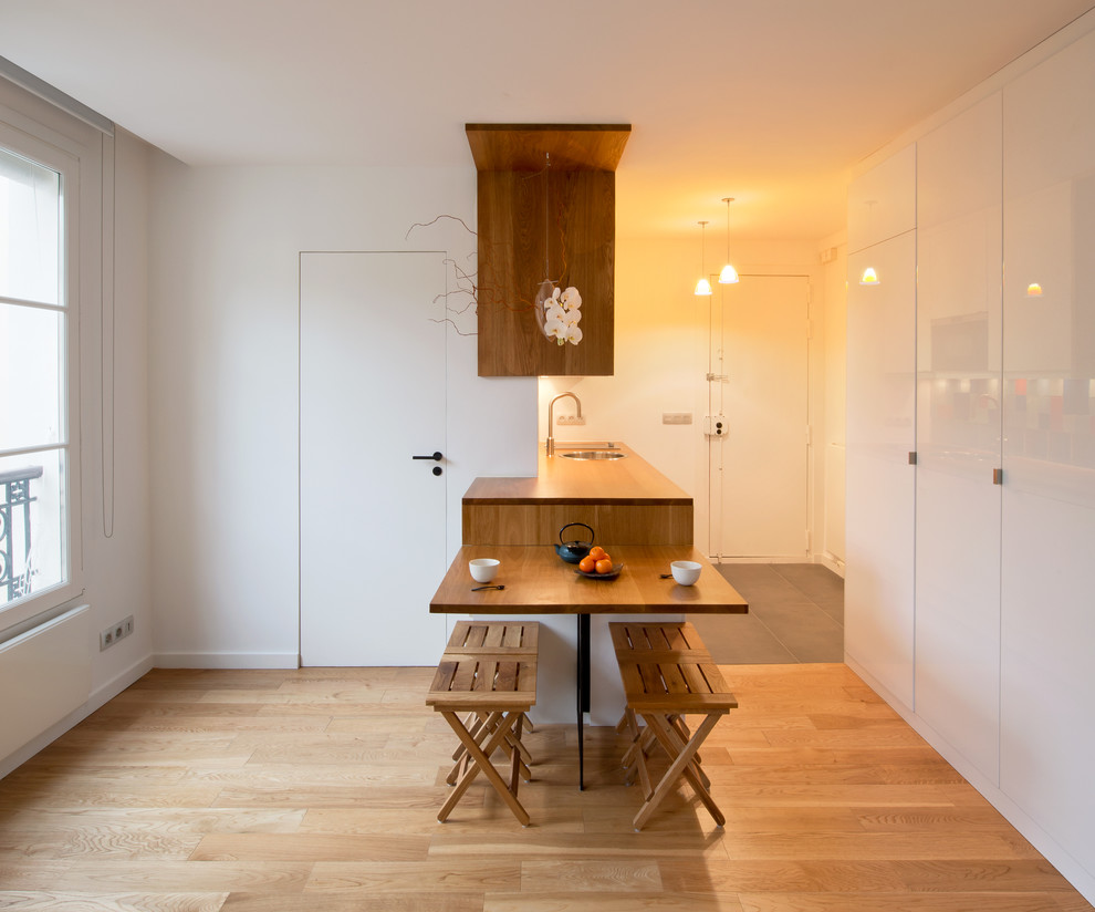 Kleine Moderne Wohnküche ohne Kamin mit weißer Wandfarbe und hellem Holzboden in Paris