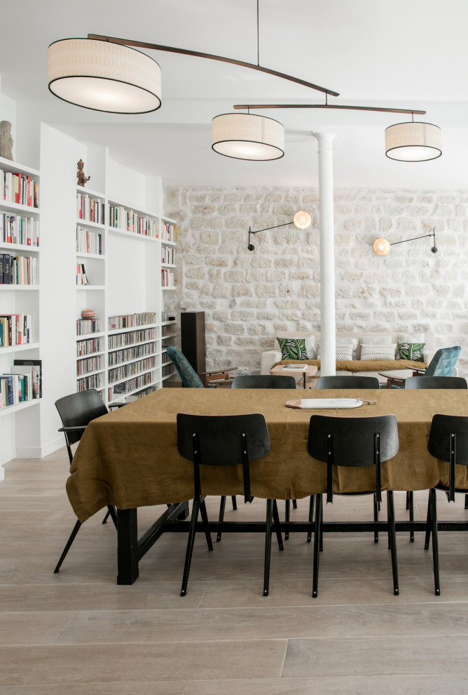 Design ideas for a scandinavian dining room in Paris with banquette seating and light hardwood flooring.