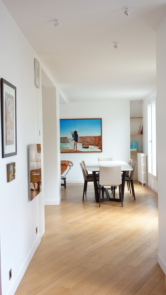 Foto di una sala da pranzo aperta verso il soggiorno minimalista di medie dimensioni con pareti bianche, parquet chiaro e pavimento beige