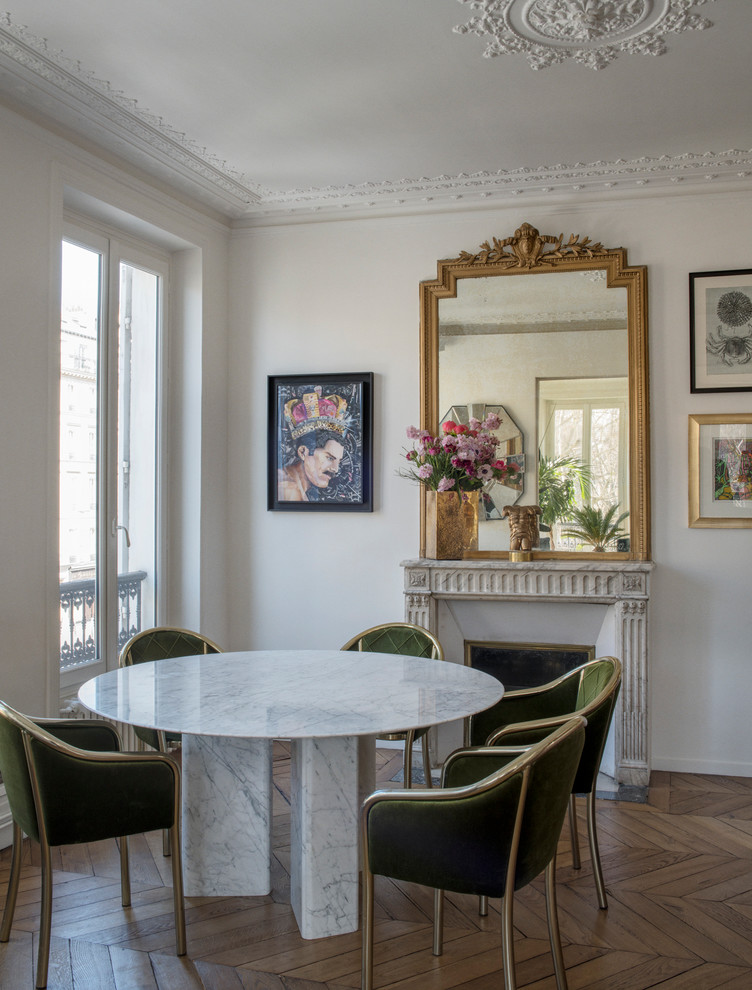 Cette image montre une salle à manger bohème fermée avec un mur blanc, un sol en bois brun, une cheminée standard et un sol marron.