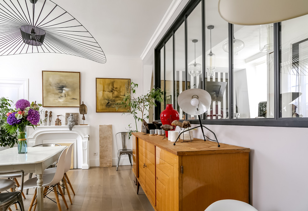 This is an example of a bohemian enclosed dining room in Le Havre with white walls, medium hardwood flooring, a standard fireplace and brown floors.