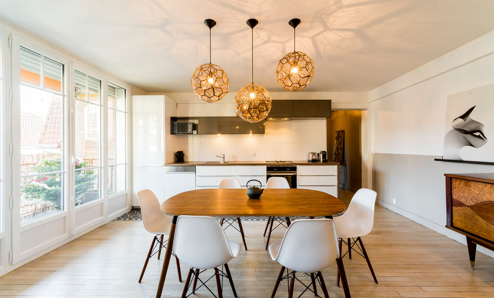 Ispirazione per una sala da pranzo aperta verso il soggiorno minimalista di medie dimensioni con pareti bianche, parquet chiaro e pavimento beige