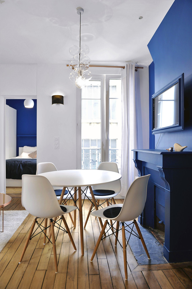 Aménagement d'une salle à manger éclectique avec un mur bleu et parquet clair.