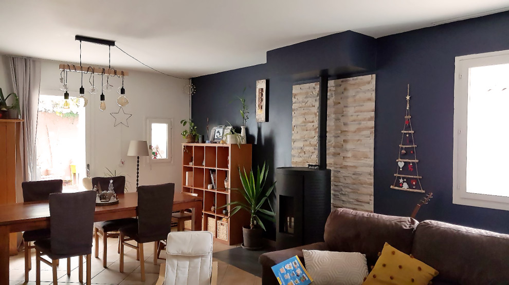 Idées déco pour une salle à manger ouverte sur le salon moderne de taille moyenne avec un mur bleu, un sol en carrelage de céramique, un poêle à bois, un manteau de cheminée en pierre de parement et un sol gris.